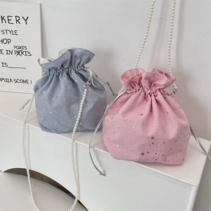 Detail showing pink and blue drawstring bags with star patterns and pearl chain straps