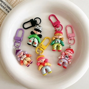 Set of five colorful cartoon girl doll keychains with matching D-ring hooks in a tray