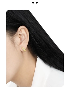 Close-up of golden clover earrings with full pavé crystals worn on a model's ear lobe