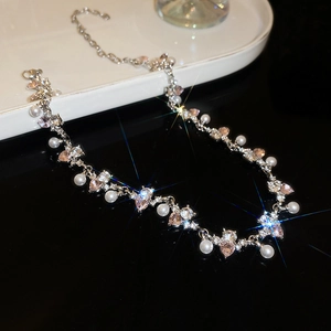 Macro view of silver necklace with white pearls, pink heart crystal and star flare effects