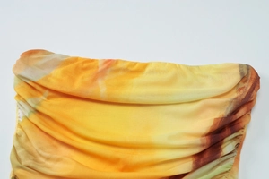 Gros plan détaillé du tissu en maille froncée avec un imprimé floral abstrait orange