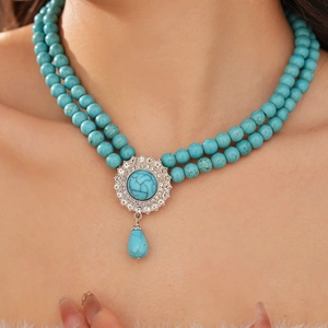 Detail of vintage double-layer turquoise necklace with diamond-set teardrop pendant on neck