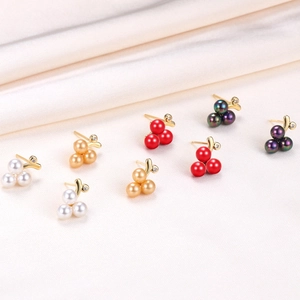 Detailed view of grape-shaped pearl earrings in white, gold, red, and purple on silk