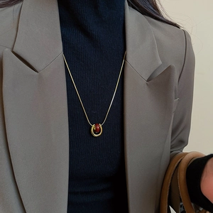 Detailed view of gold plated U-shaped pendant necklace with deep red bead on model