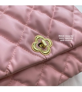 Detail of pink quilted leather handbag featuring a decorative golden flower twist lock closure