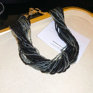 Dettaglio della collana bohémien a più fili in perline con chiusura dorata su carta