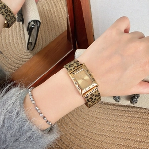 Close-up of leopard print metal strap and gold square quartz watch worn on a wrist
