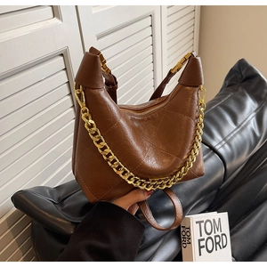 Detail of brown quilted faux leather bucket bag with chunky gold chain strap and shoulder strap