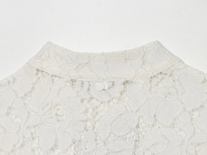 Detail shot of white lace blouse neckline with elegant floral embroidery and texture