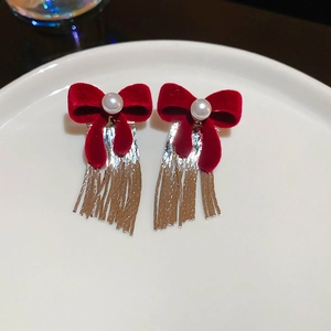 Dettaglio di orecchini a fiocco in velluto rosso con perla bianca e nappine argento