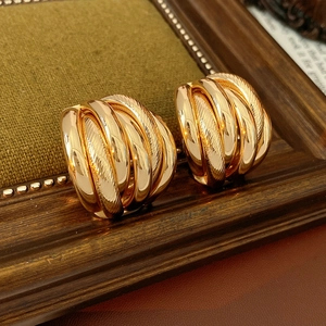 Macro shot of layered gold hoop earrings with brushed texture on vintage wood
