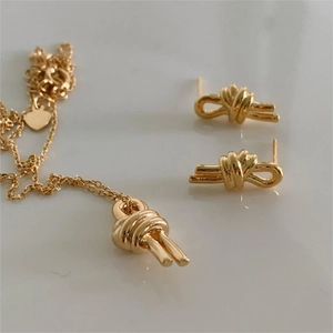 Detailed close-up of gold knot jewelry set featuring matching necklace and stud earrings