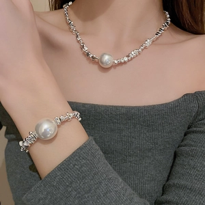 Detail of silver irregular metal chain necklace and bracelet set with round white pearls