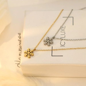 Elegant 18k gold and silver snowflake pendant necklaces displayed on a gift box