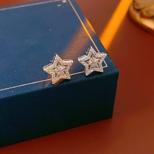 Macro view of silver star stud earrings with pave zircon on a blue jewelry box