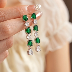 Détail de boucles d'oreilles argentées avec zircons verts et blancs en poire