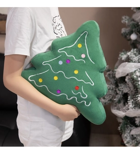 Detail of soft green plush Christmas tree pillow held by hand with festive embroidery
