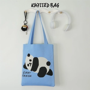 Detail of light blue knitted tote bag featuring a cute panda design on a wall hook