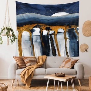 Detail of abstract mountain and moon tapestry hanging above a modern grey sofa