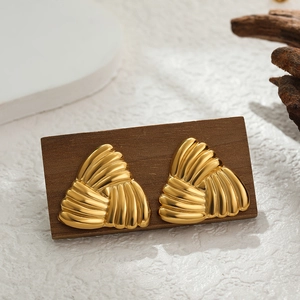 Detailed view of gold-plated triangular earrings with woven texture on a dark wooden surface