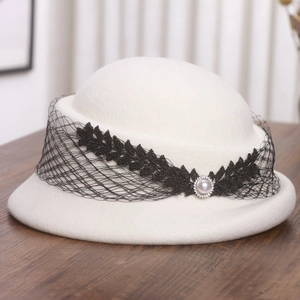 Détail d'un béret en laine blanche avec dentelle noire et perle ornée d'un voile