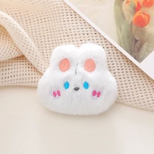 Close-up of a soft white plush bunny brooch with detailed pink and blue embroidery