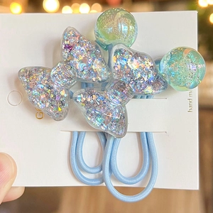 Macro detail of light blue hair ties with colorful glitter filled resin bow and ball charms