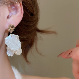 Detail of golden sunburst earrings with brown stone and layered pearlescent petals