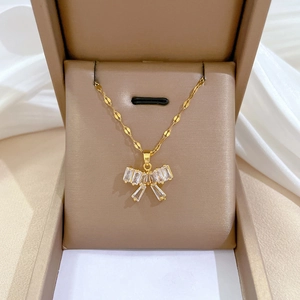 Elegant gold titanium steel necklace with sparkling crystal bow pendant in a jewelry box