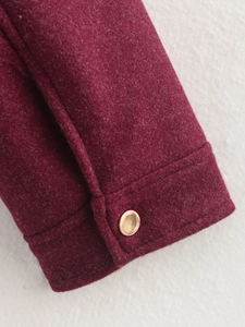 Detailansicht der weinroten Tweed-Jackenmanschette mit dekorativem goldenem Metallknopf
