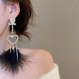 Close-up of long heart stud earrings with silver tassels and black feather dangles