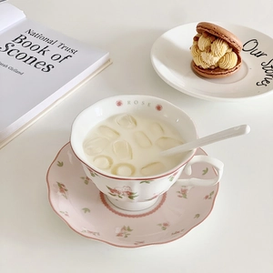 Close-up of ceramic coffee cup with pink floral patterns and elegant wavy edges