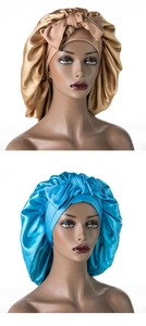 Detail of silk satin sleep caps with wide elastic bands and decorative bowknots in gold and blue