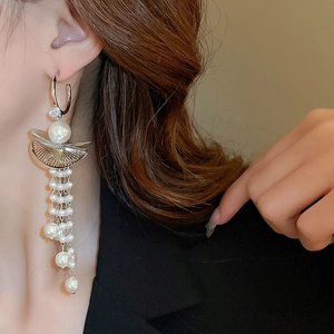 Macro detail of vintage gold fringe earrings with pearls and rhinestones on model