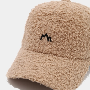 Detailed close-up of fluffy beige teddy fleece baseball cap with black peak embroidery