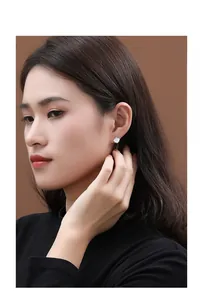 Detailed view of minimalist S925 silver ginkgo leaf earrings with white shell on ear