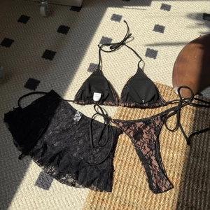Vue détaillée d'un ensemble bikini 3 pièces en dentelle noire avec jupe transparente