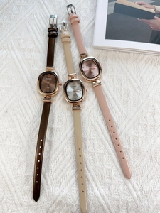 Close-up of vintage square quartz watches with brown, beige, and pink leather straps