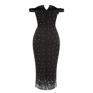 Détail de perles blanches sur le dos d'une robe noire à épaules dénudées avec fermeture éclair