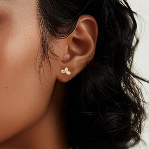 Close-up of three-petal golden flower stud earrings with sparkling crystals on ear