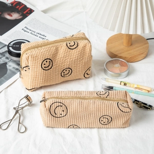 Detail of corduroy makeup bag set with embroidered smiley faces and textured stripes