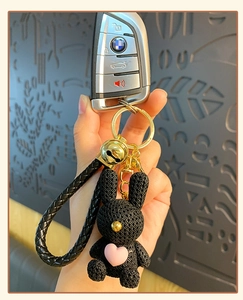 Close-up of black woven resin rabbit keychain with pink heart charm and gold bell details