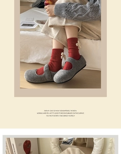 Detail of red knit socks with white bows paired with grey wool Mary Jane indoor slippers
