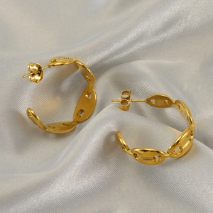 Golden stainless steel pig nose hoop earrings on elegant silk fabric background