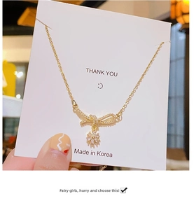 Detailed macro of gold bow pendant necklace with sparkling daisy flower charms