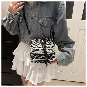 Chic black and white woven bucket bag with geometric patterns and drawstring closure