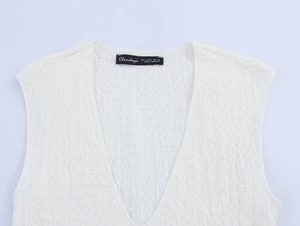 Detail of white sleeveless top showing textured fabric and size label in close-up shot