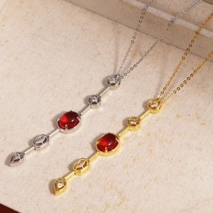 Detail of red gemstone pendants in gold and silver finish on linen background