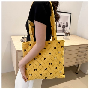 Detail of yellow corduroy tote bag with black bow and quilted diamond pattern