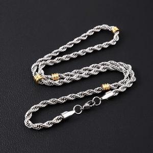 Detailed close-up of a silver stainless steel chain necklace with gold bead accents